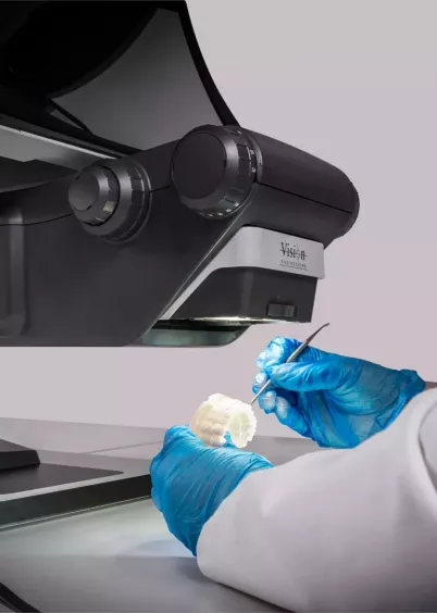 Ręce technika w&nbsp;rękawiczkach kontrolujące model zębowy pod mikroskopem 3D FHD DRV-Z1 w&nbsp;laboratorium stomatologicznym