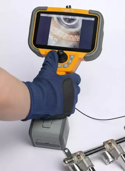 Operator w&nbsp;rękawicy obsługuje joystick endoskopu RVI Inspector Pro; obraz z&nbsp;kamery widoczny na ekranie urządzenia.