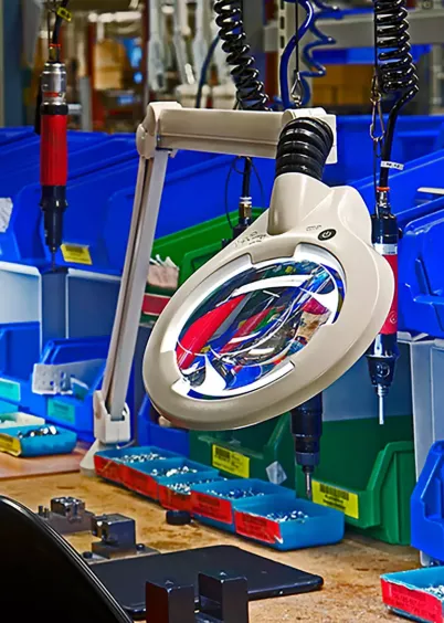 Dwie lampy z&nbsp;lupą Luxo CIRCUS LED oświetlające linię montażową