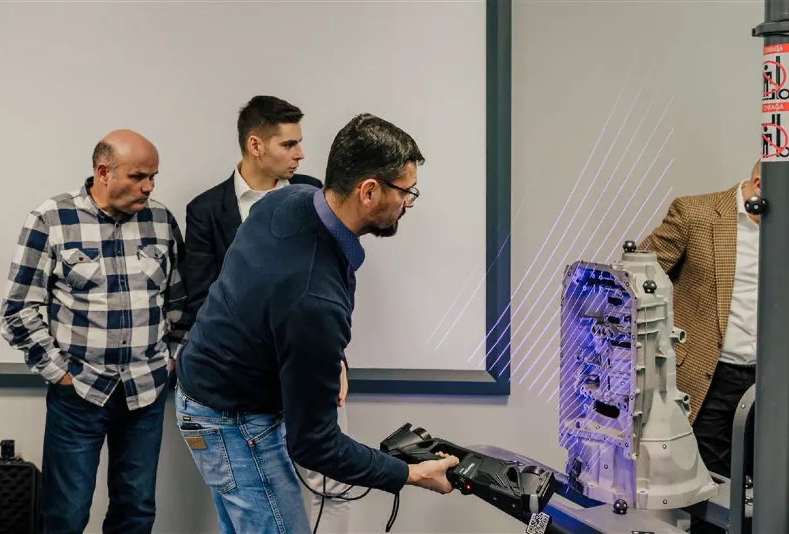 Demonstracja skanera 3D HandySCAN 3D MAX podczas skanowania obudowy maszyny – linie laserowe i&nbsp;zespół operatorów