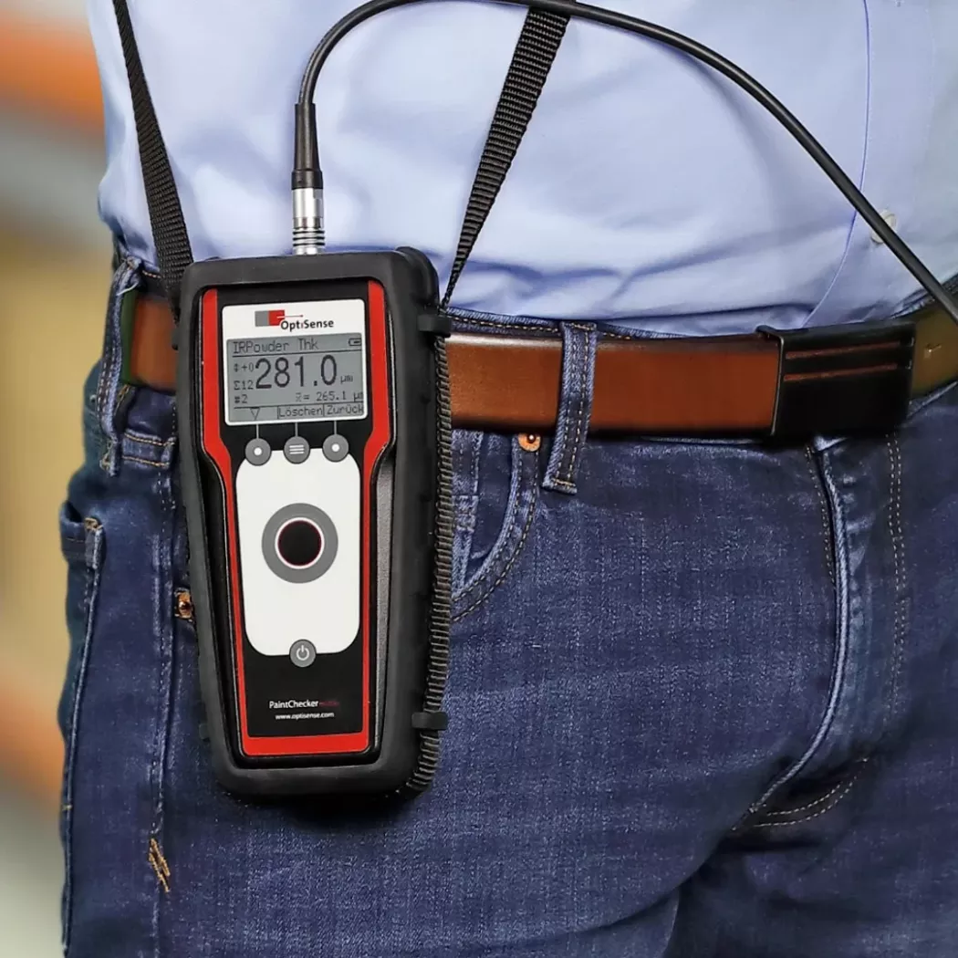 Przenośny miernik grubości powłok OptiSense PaintChecker Mobile przypięty do paska podczas pomiaru