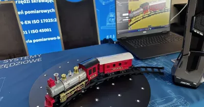 Model pociągu na obrotnicy obok laptopa – demonstracja procesu skanowania 3D.